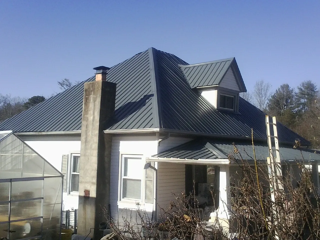 Dark blue standing seam metal roof on a white farmhouse with dormer — Slate & Tile Roof Repair by Roofing Brothers in Bellefontaine