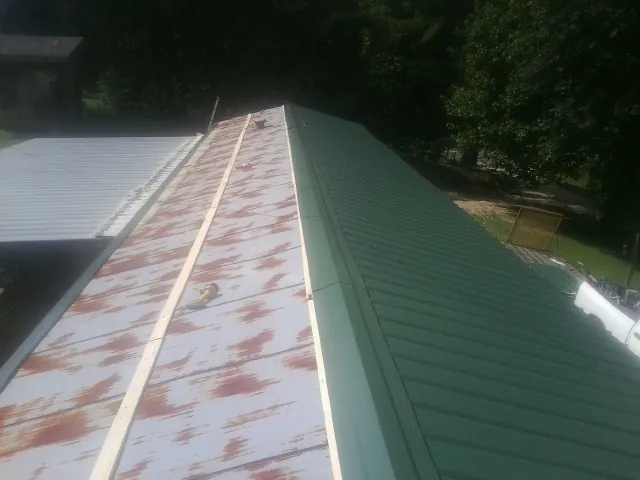 Old rusted panels beside newly installed green metal roofing — Wind Damage Roof Repair by Roofing Brothers in Bellefontaine